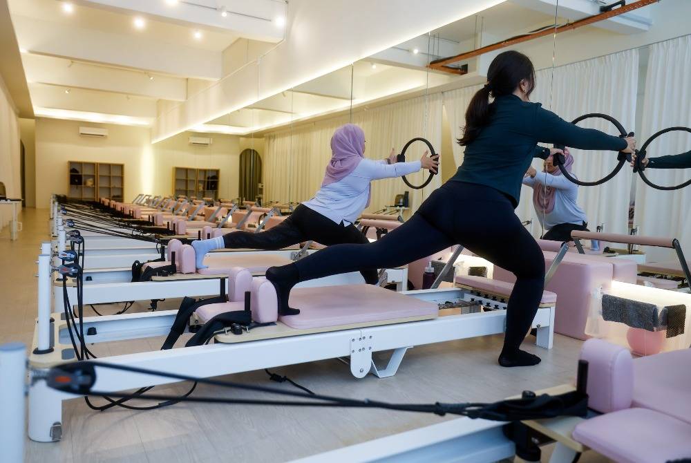 Dr Nur Rafidah Mohamed Ali and Ili Izzati Setu perform stretching and Pilates exercises during a recent visit to the Pilates Collective studio. Photo by Bernama