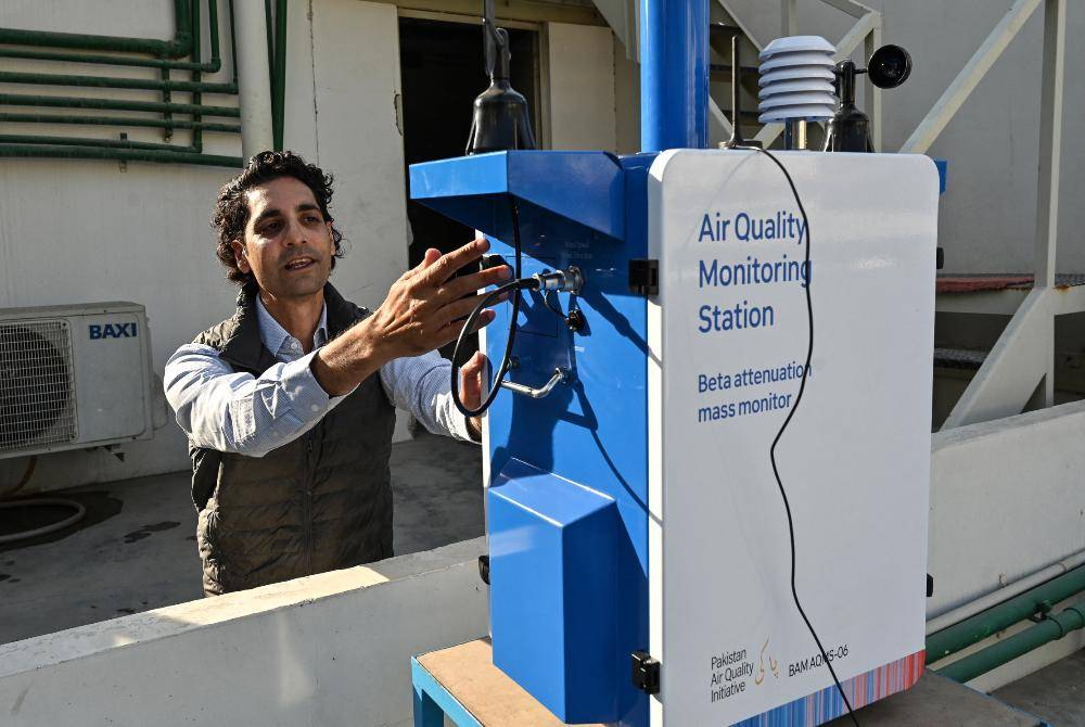 This photograph taken on Jan 9, 2026 shows Abid Omar, an engineer, explaining about the air-quality monitoring station installed on a rooftop of his office in Karachi. - (Photo by ASIF HASSAN / AFP)