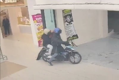 Police are hunting two local men suspected of being involved in an armed robbery at a gold shop inside a shopping mall in Bandar Baru Nilai here last night. Photo: Screenshot of CCTV recording.