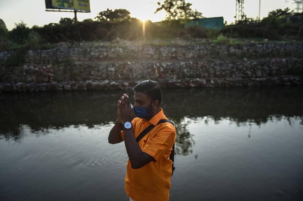 A Hindu devotee performs a religious ritual ahead of the Thaipusam festival outside a temple in Batu Caves on the outskirts of Kuala Lumpur on January 17, 2022. (Photo by Arif Kartono / AFP)