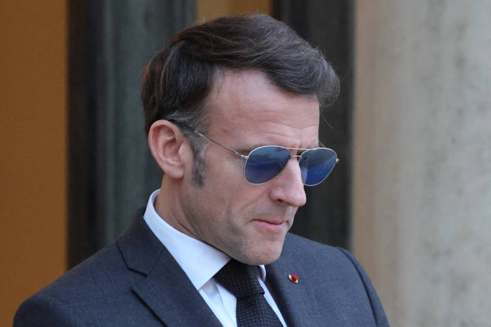 France's President Emmanuel Macron wearing sunglasses reacts as he waits for Lebanon's Prime Minister's arrival prior to their meeting at the Elysee presidential palace in Paris, on January 23, 2026. (Photo by Ludovic MARIN / AFP)