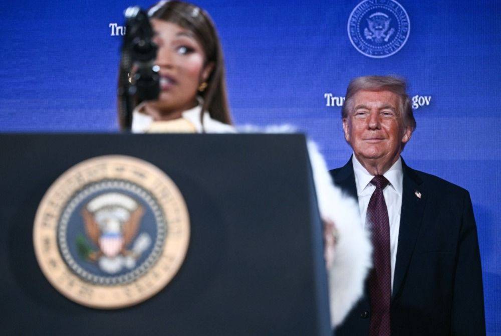 US President Donald Trump (R) looks on as Trinidadian rapper and singer-songwriter Nicki Minaj speaks during an event on 'Trump Accounts' at the Andrew W. Mellon Auditorium in Washington, DC. Photo by Brendan Smialowski/AFP