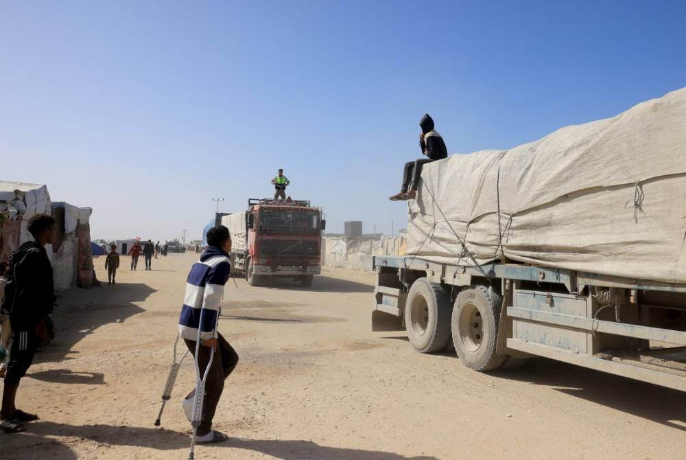 Palestinians look on as trucks carrying humanitarian aid arrive in Khan Yunis in the southern Gaza Strip, after passing through the Rafah border crossing from Egypt, on Feb 1, 2026. - (Photo by Bashar Taleb / AFP)
