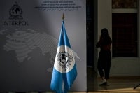 A woman walks near an Interpol flag ahead at the International Criminal Police Organisation Interpol headquarters in Lyon, eastern France, on June 9, 2025. (Photo by OLIVIER CHASSIGNOLE / AFP)