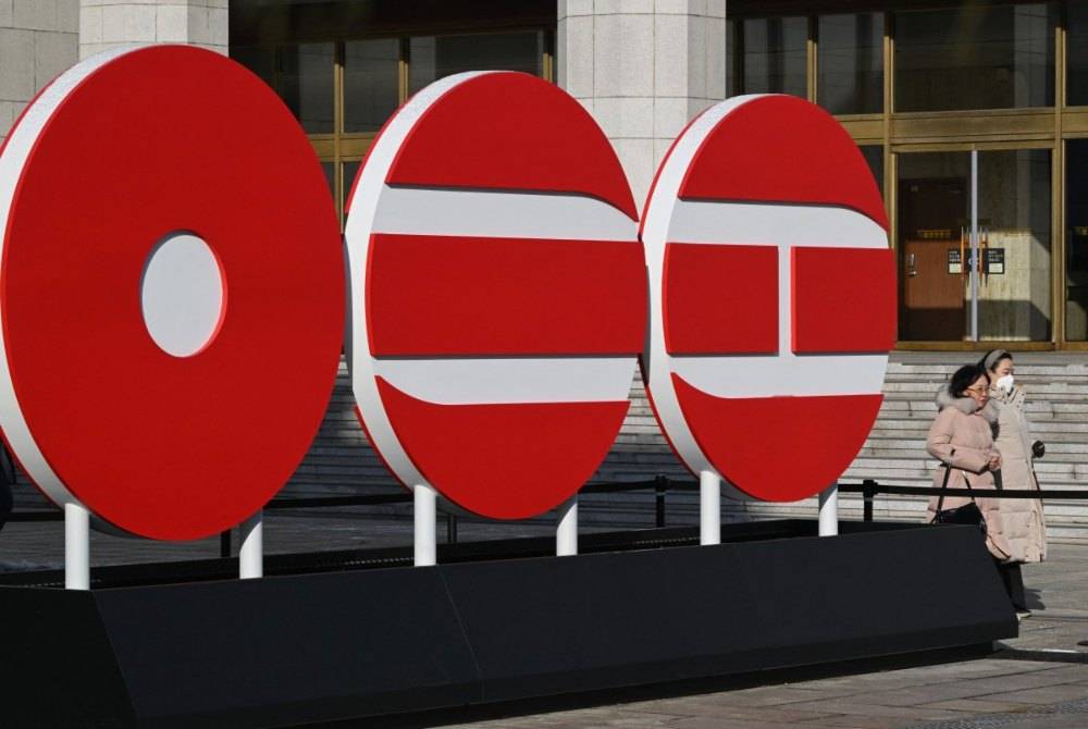 Pedestrians walk past the logo of BTS' 2026 album at Gwanghwamun Square in Seoul on Jan 14, 2026. - (Photo by Jung Yeon-je / AFP)