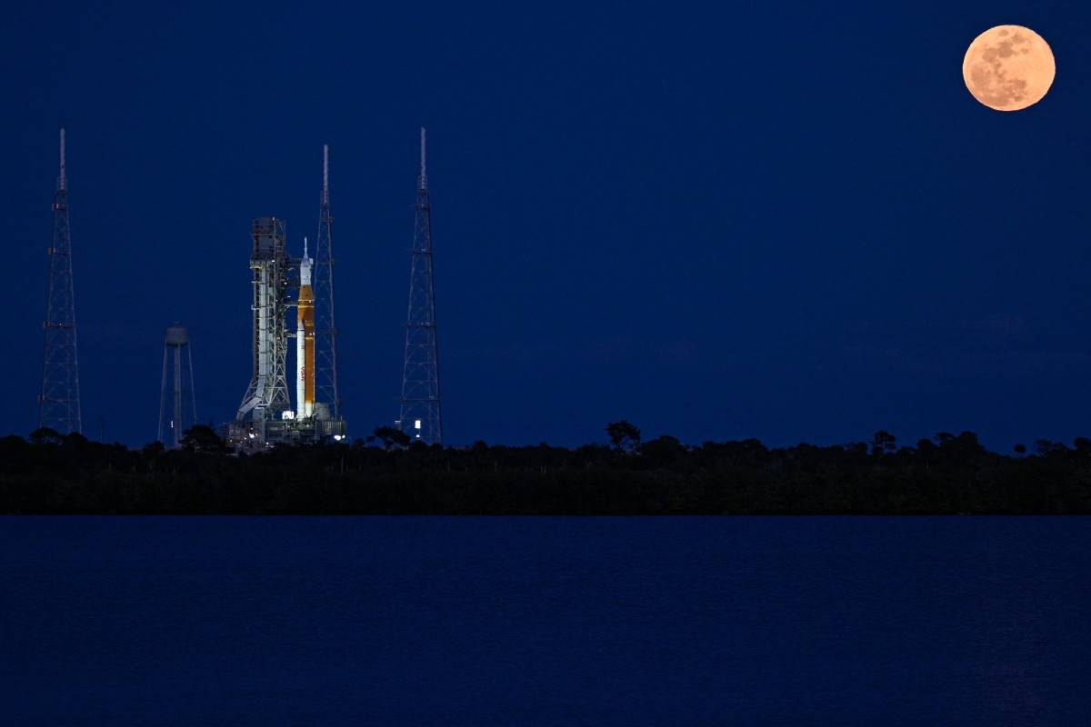 A full moon rises as the Space Launch System (SLS) rocket and the Orion spacecraft, integrated for the Artemis II mission, are seen at Launch Pad 39B at the Kennedy Space Center in Cape Canaveral, Florida, on February 1, 2026 ahead of the first crewed mission to the Moon in more than 50 years. (Photo by Miguel J. Rodriguez Carrillo / AFP)