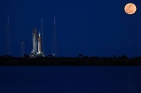 A full moon rises as the Space Launch System (SLS) rocket and the Orion spacecraft, integrated for the Artemis II mission, are seen at Launch Pad 39B at the Kennedy Space Center in Cape Canaveral, Florida, on February 1, 2026 ahead of the first crewed mission to the Moon in more than 50 years. (Photo by Miguel J. Rodriguez Carrillo / AFP)