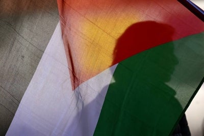 A silhouette of a demonstrator is seen behind a Palestinian flag during a protest in solidarity with Palestinians and to condemn the interception of the Global Sumud Flotilla by the Israeli army in Bogota on Oct 2, 2025. - (Photo by RAUL ARBOLEDA / AFP)