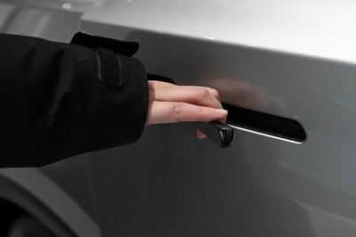 A woman opens the door for a Tesla Model YL electric vehicle at a showroom in Beijing on February 3, 2026. China will ban hidden door handles on cars sold in the country from next year, phasing out the minimalist design popularised by Tesla over safety concerns. (Photo by Pedro Pardo / AFP)