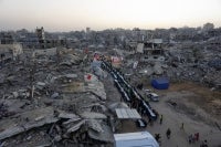 Palestinians gather for a mass fast-breaking iftar meal organised by the Turkish IHH Foundation, amid the rubble of destroyed buildings in Gaza City on Feb 18, 2026. - (Photo by OMAR AL-QATTAA / AFP)