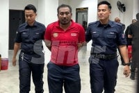 Nik Muhammad Afiq (centre) is taken out of the court lockup. 