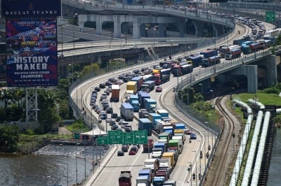Trucks carrying goods from Malaysia wait to enter the Woodlands land border checkpoint into Singapore on June 29, 2022. (Photo by Roslan RAHMAN / AFP)