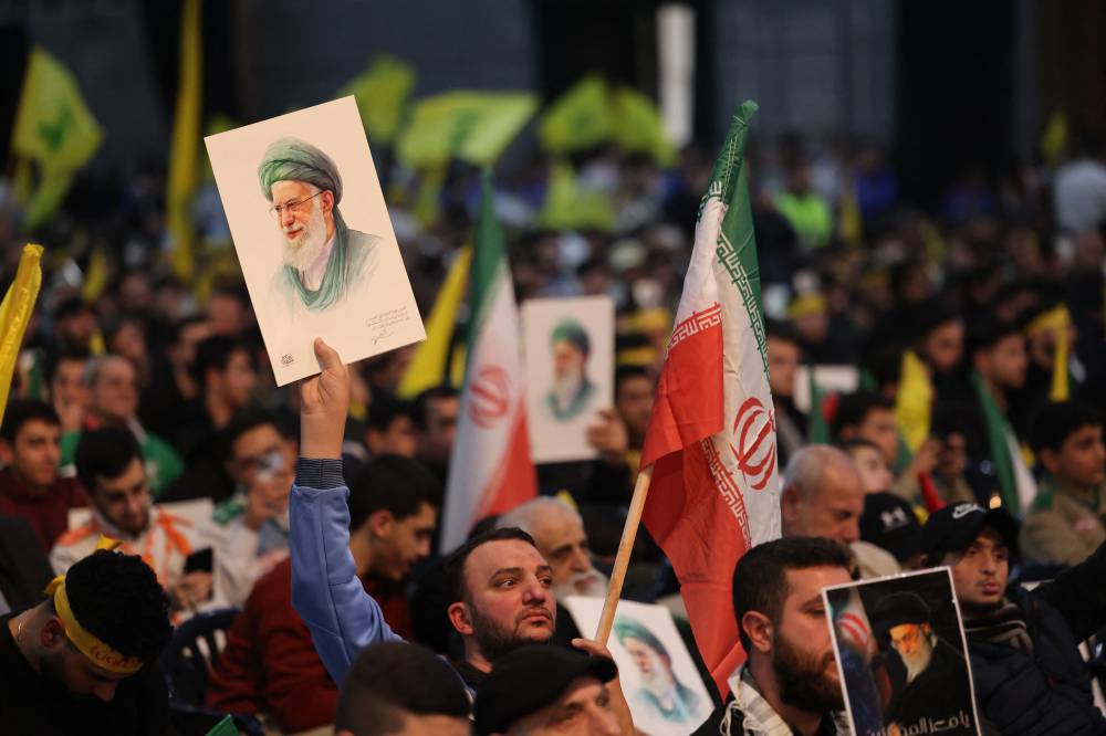 Hezbollah supporters hold portraits of Iran's Supreme Leader Ayatollah Ali Khamenei during a rally to show their solidarity with Iran, in the southern suburb of Beirut on January 26, 2026. Hezbollah chief Naim Qassem said on January 26, that any attack on the group's backer Tehran would also target the militants, and warned that any new war on Iran would ignite the region. (Photo by Anwar AMRO / AFP)