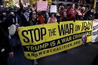 People hold signs and a banner during the "Stop the War on Iran" protest at Times Square in New York City on February 28, 2026. (Photo by Leonardo MUNOZ / AFP)