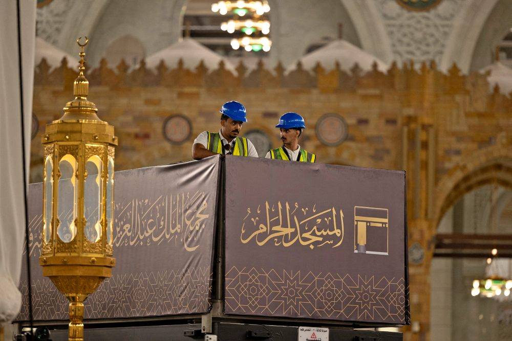 Saudi workers install the new Kiswa, a black silk and gold-embroidered cloth that covers the Kaabah, at the Grand Mosque in the holy city of Mecca on June 15, 2026, marking the Islamic New Year. Photo by AFP