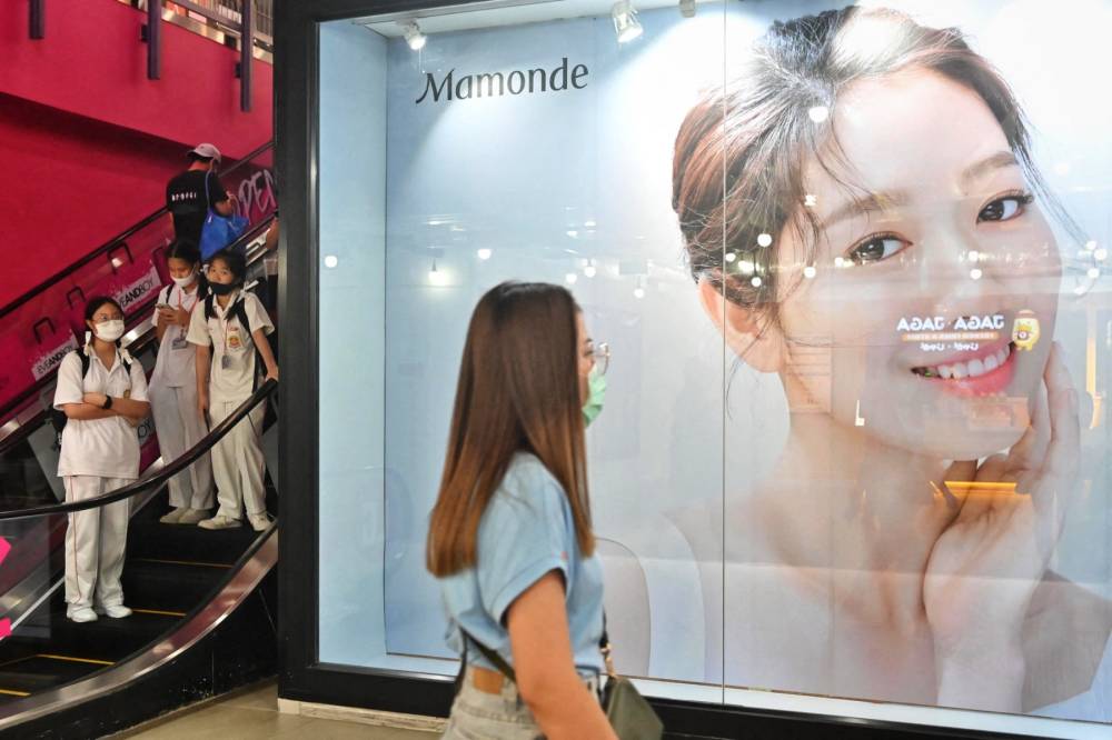 A woman walks past an advertisement for South Korean skincare brand Mamonde in front of a beauty store. (AFP photo)
