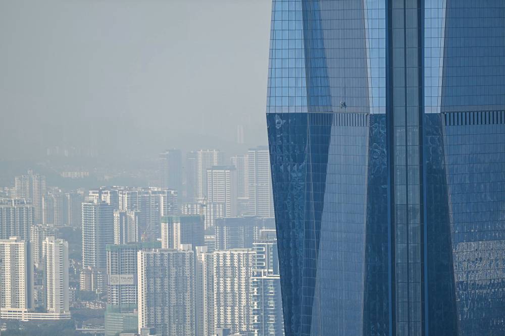 A worker cleans the windows of Warisan Merdeka Tower (KL118) the second tallest building in the world, in Kuala Lumpur on August 19, 2025. - (Photo by Mohd RASFAN / AFP)