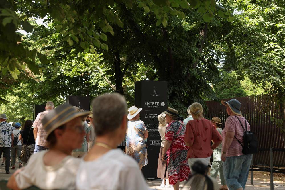 Pedestrians walk by an entrance of the Eiffel Tower during its early closing due to heatwave in Paris on June 23. Photo by AFP