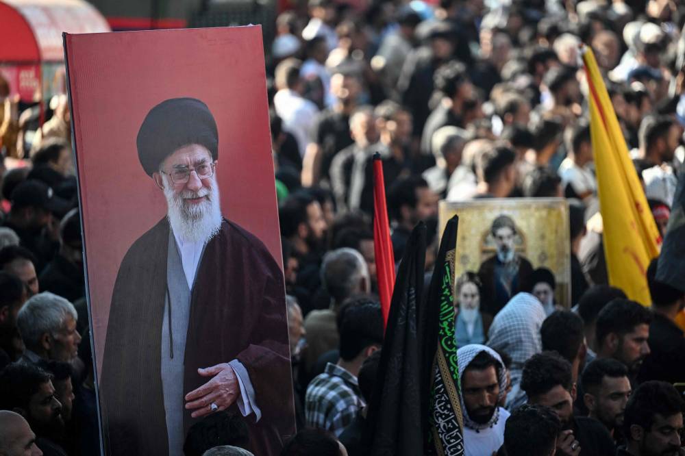 Kashmiri Shia mourners hold a portrait of Iran's late supreme leader Ayatollah Ali Khamenei during a religious procession on the seventh day of Ashura during the Islamic holy month of Muharram in Srinagar on June 23, 2026. - (Photo by TAUSEEF MUSTAFA / AFP)