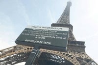 This photograph, taken through a window shows the Eiffel Tower with a giant screen announcing its early closing due to heatwave in Paris on June 23, 2026. - (Photo by CHARLOTTE SIEMON / AFP)