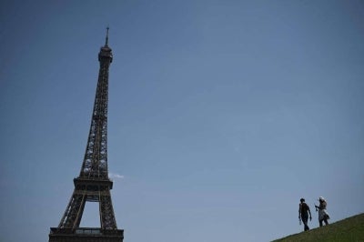 Pedestrians hold a bottle of water as they walk near the Eiffel Tower during a heatwave in Paris on June 22. Photo by AFP
