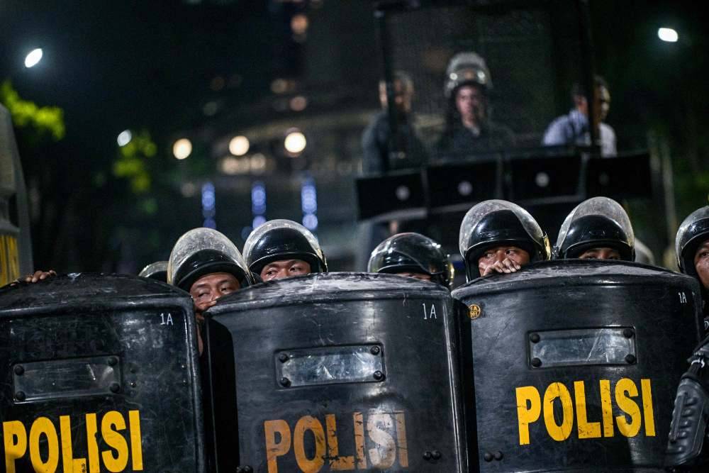 Riot police stand guard following clashes during protest against a rise in non-subsidised fuel prices, inefficient government spending and military involvement in civilian affairs and the government's free school meals programme (MBG) in Surabaya. Photo by Juni Kriswanto/AFP