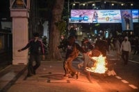 A student throws a fire box at riot police during protest against a rise in non-subsidised fuel prices, inefficient government spending and military involvement in civilian affairs and the government's free school meals programme (MBG) in Surabaya on June 26, 2026. Photo by Juni Kriswanto/AFP