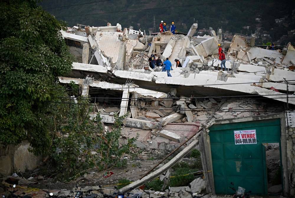 Rescuers search for possible victims at a collapsed building following twin earthquakes, in Los Corales, La Guaira state, some 40km northeast of Caracas, on June 27, 2026. - (Photo by FEDERICO PARRA / AFP)