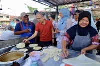 Communications Minister Datuk Fahmi Fadzil, who is also the MADANI Government spokesperson, alongside PH N16 Sungai Balang candidate, Soraya Badaruddin, spent time with locals at the Parit Jawa market during a breakfast programme and FIFA World Cup 2026 football viewing event today. - Photo by Bernama