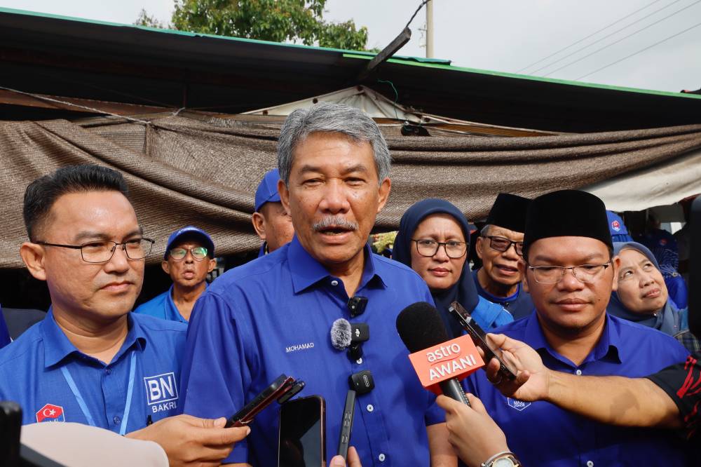 BN deputy chairman Datuk Seri Mohamad Hasan after greeting voters who were having breakfast at a stall in Jalan Sungai Abong, Muar with BN candidate for Simpang Jeram constituency Datuk Azman Ismail and BN candidate for Bukit Naning Mohd Ghazali Sabari @ Atan. - Photo by Bernama