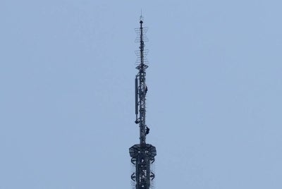 Two people climb on the spire of the Empire State Building in New York on July 1, 2026. Two people climbed to the top of the Empire State Building on July 1 and unfurled a banner appearing to read "when the power of love beats the love of power the world knows peace," video published by US media showed. - (Photo by TIMOTHY A. CLARY / AFP)