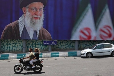 Motorists ride past a giant billboard bearing a picture of Iran's late supreme leader Ayatollah Ali Khamenei ahead of his funeral, in Tehran on July 2, 2026. - (Photo by AFP)