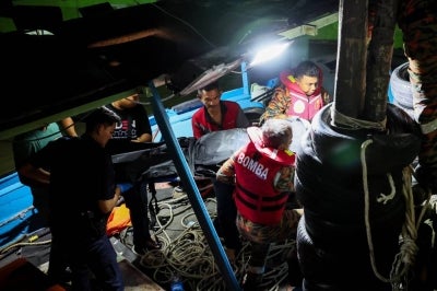 Rescuers carry the body of assistant skipper Ahmad Nasaruddin Mohmad Jalil, 37, who died after the squid jigging boat he was on sank about nine nautical miles off Kuala Nerus, at the LKIM Kampung Batin Jetty last night. - Photo by Bernama 