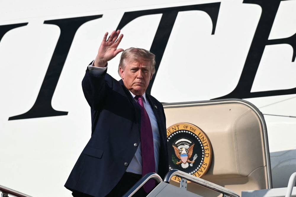 US President Donald Trump waves as he boards Air Force One before departing Joint Base Andrews (Photo by Mandel NGAN / AFP)