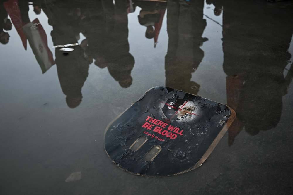 Mourners stand next to a placard calling for revenge as they gather to pay tribute to Iran's slain supreme leader Ayatollah Ali Khamenei at the Grand Mosalla. Photo by AFP