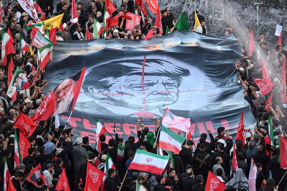 People hold up a revenge banner against the US president as they gather to mourn Iran's slain supreme leader Ayatollah Ali Khamenei at the Grand Mosalla. Photo by AFP