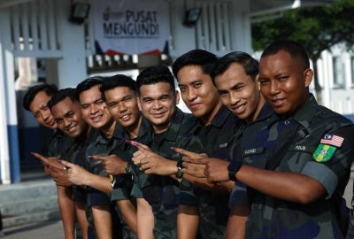 Members of the General Operations Force (GOF) show their inked fingers after casting their votes during the early voting process for the 16th Johor state election at the GOF Battalion 5 Camp in Simpang Renggam today. - Photo by Bernama