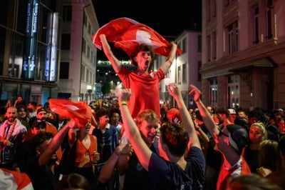 Switzerland supporters euphoric after their team's victory in the 2026 World Cup round of 16 football match between Switzerland and Colombia,(Photo by Fabrice COFFRINI / AFP)