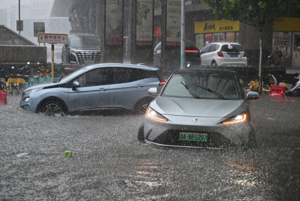 Cars are driven along a flooded street in Beijing on July 7, 2026. - (Photo by ADEK BERRY / AFP)