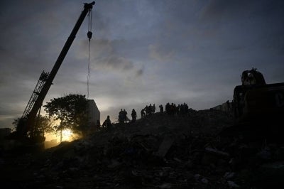 Rescuers and volunteers stand on the rubble of collapsed buildings following the June 24 earthquakes in Caraballeda, La Guaira state, Venezuela on July 8, 2026. - (Photo by FEDERICO PARRA / AFP)