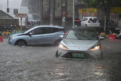 Cars are driven along a flooded street in Beijing on July 7, 2026. - (Photo by ADEK BERRY / AFP)