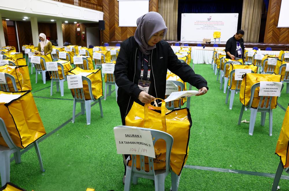 An Election Commission officer conducts a final check on the yellow bags containing ballot boxes and important polling documents, to be distributed to the Perling State Legislative Assembly constituency for the Johor state election tomorrow, during an inspection at the Official Vote Tallying Centre for Perling at Dewan Jubli Intan, Johor Bharu, today. - Photo by Bernama