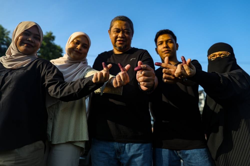 (Illustrative Purposes) A family of five - Md Faizal Mamolah (centre), his wife and their three children - display their ink-stained fingers after casting their votes at the Sekolah Kebangsaan Seri Melati polling center during the 16th Johor State Election today. (BERNAMA PHOTO) 