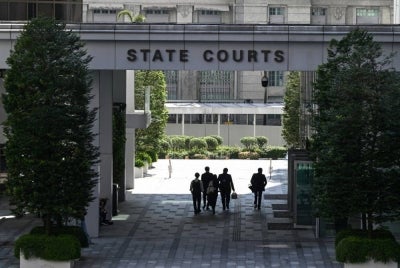 People walk through the State Court building in Singapore on June 26, 2026. - (Photo by ROSLAN RAHMAN / AFP)