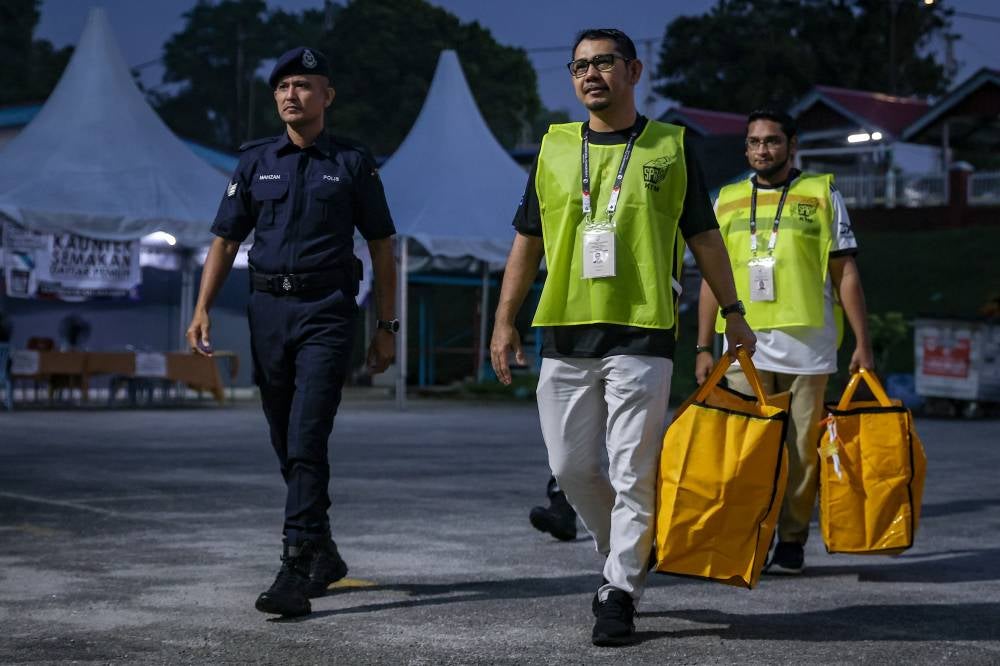 Election Commission (EC) officials, accompanied by police personnel, transport ballot boxes to the polling station for the N47 Kempas state constituency at Sekolah Kebangsaan Seri Melati during the 16th Johor State Election on July 11, 2026. (BERNAMA PHOTO)