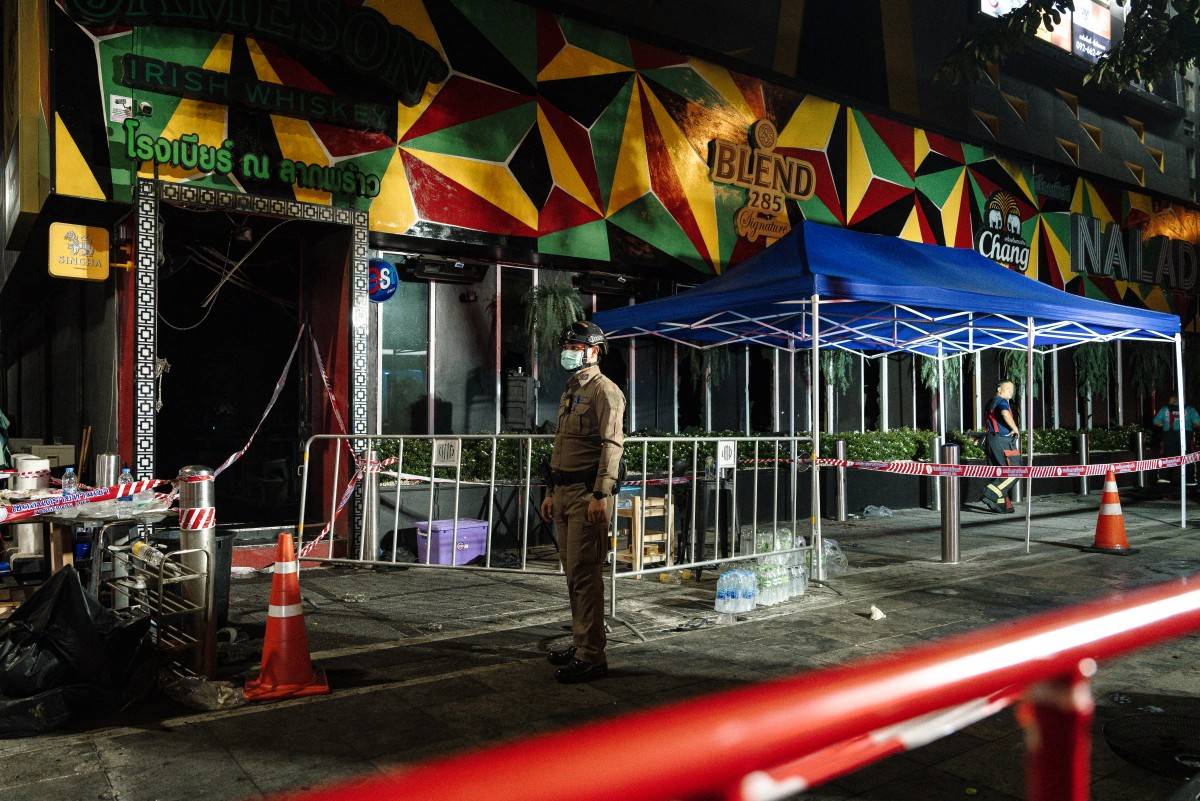 Police stand guard outside the burnt remains of a bar in Bangkok early on July 13, 2026, after a fire in the Rong Beer Na Lat Phrao bar killed at least 27 people late Sunday night. AFP photo.