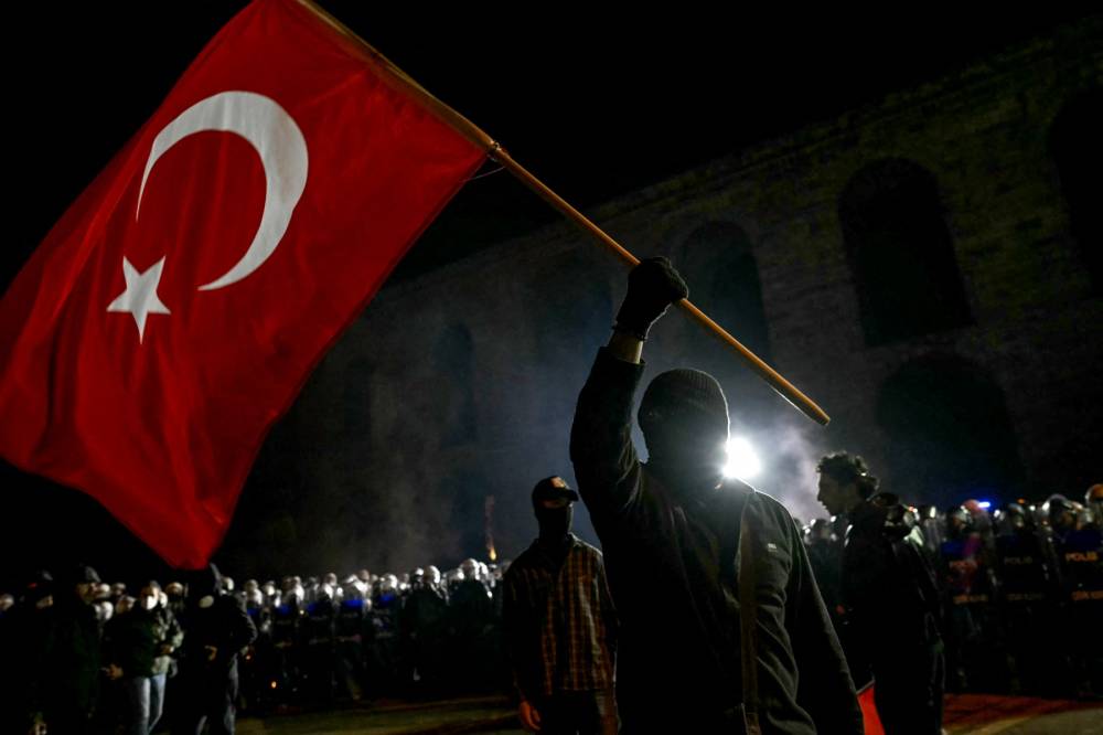 A protester waves a Turkish flag in front of Turkish riot police during a demonstration outside Istanbul's city hall (Photo by OZAN KOSE / AFP)