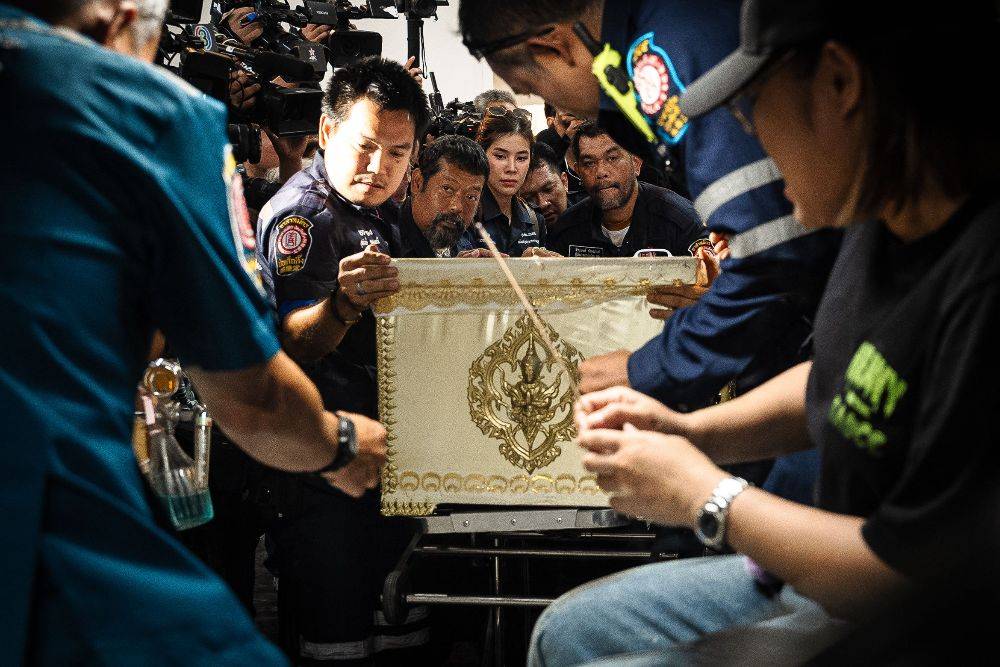 Responders transport a coffin bearing the remains of a victim killed in a bar fire, at the Police General Hospital in Bangkok on July 14. Photo by Chanakarn Laosarakham/AFP