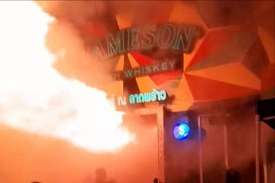 A massive fire in a Bangkok bar late on July 12 night killed at least 27 people and injured dozens, sending screaming patrons fleeing as flames shot from the entrance. Photo by Handout/Courtesy of Kan Kutirat/AFP