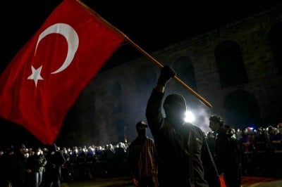 A protester waves a Turkish flag in front of Turkish riot police during a demonstration outside Istanbul's city hall (Photo by OZAN KOSE / AFP)